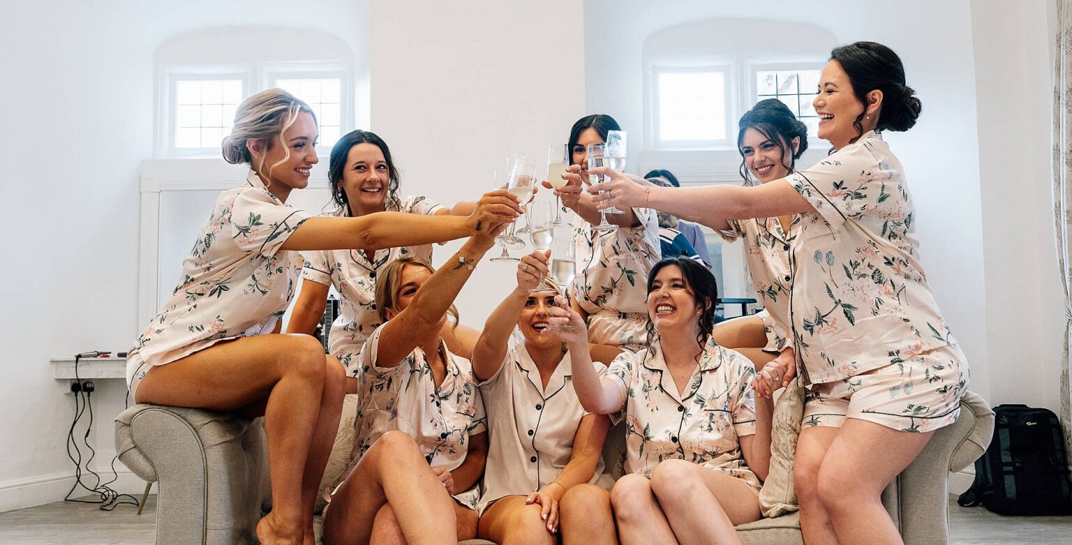 bridesmaids sit on sofa with bride and celebrate the wedding at Crowcombe Court with prosecco