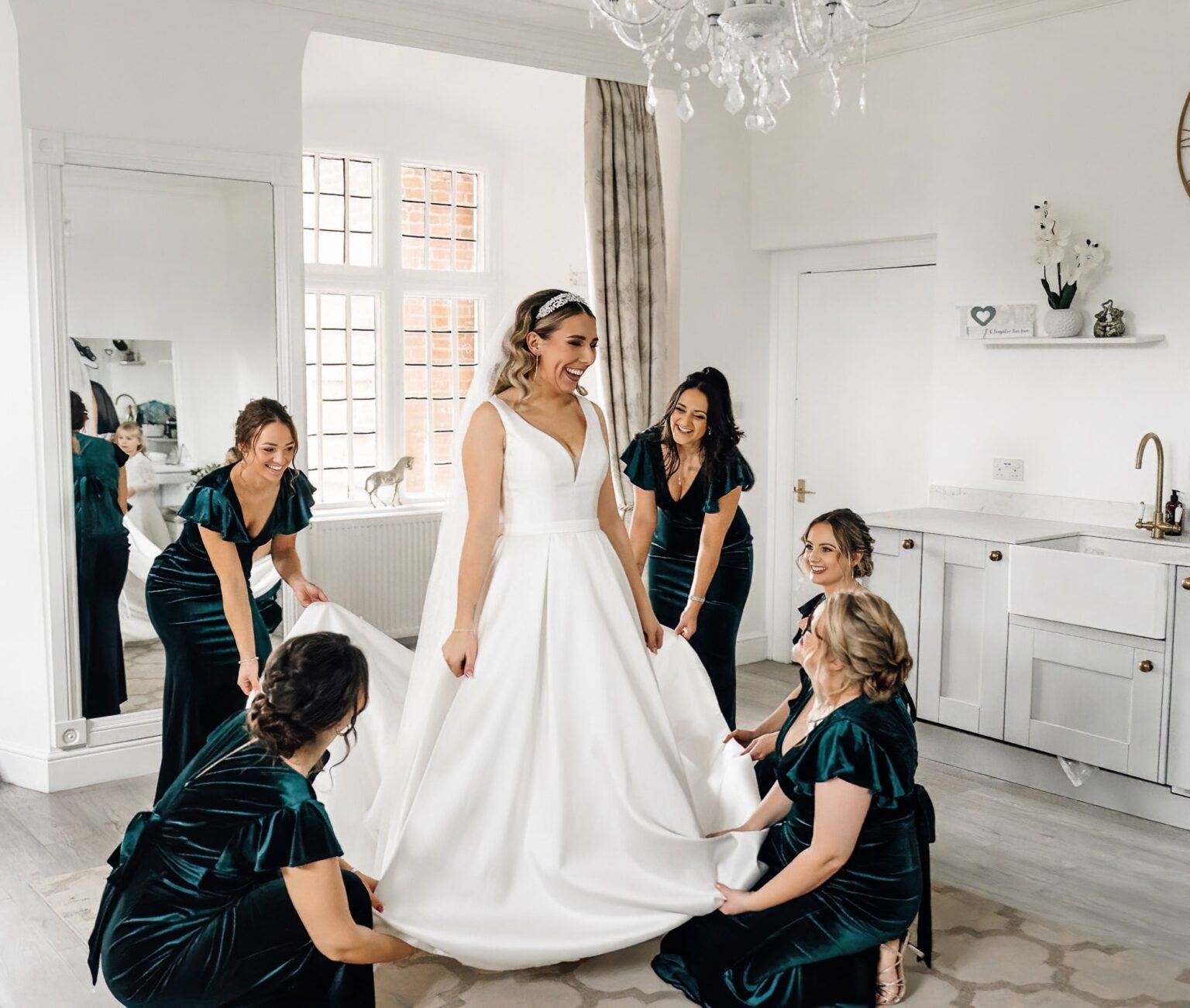 Bridesmaids adjusting bride's dress at Crowcombe court before her wedding