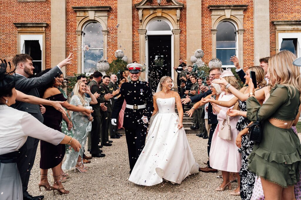 Confetti being thrown at newlyweds as they walk down the path after their Crowcombe Court wedding ceremony